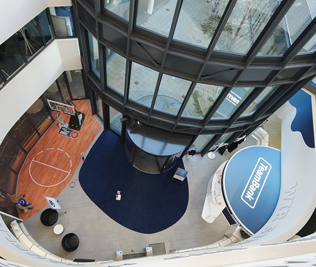 Foyer von oben mit Glasfassade, Basketballkorb und TeamBank-Schriftzug.