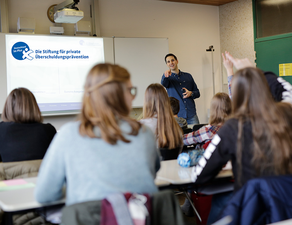 Referent der Stiftung Deutschland im Plus steht vor einer Schulklasse.